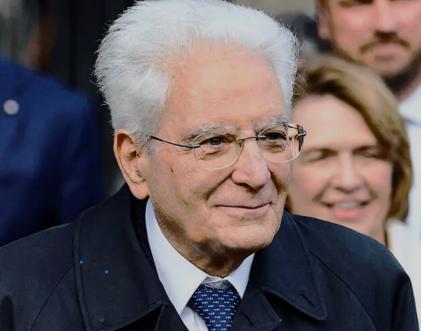 An elderly man with white hair and glasses smiling.